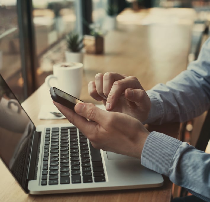 man in a coffee shop using a mobile phone and a laptop